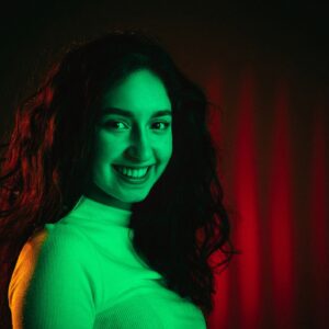 Cinematic silhouette-style portrait on dark charcoal background with subtle green lighting accents